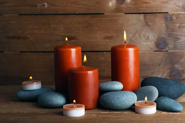 Prachtige spa stenen met kaarsen op houten achtergrond — Stockfoto