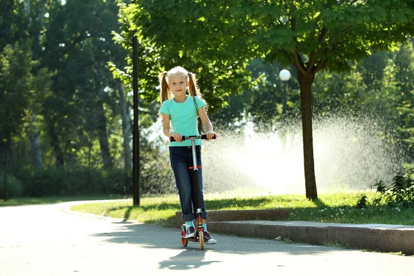 Small girl riding on scooter in park — Stock Photo, Image