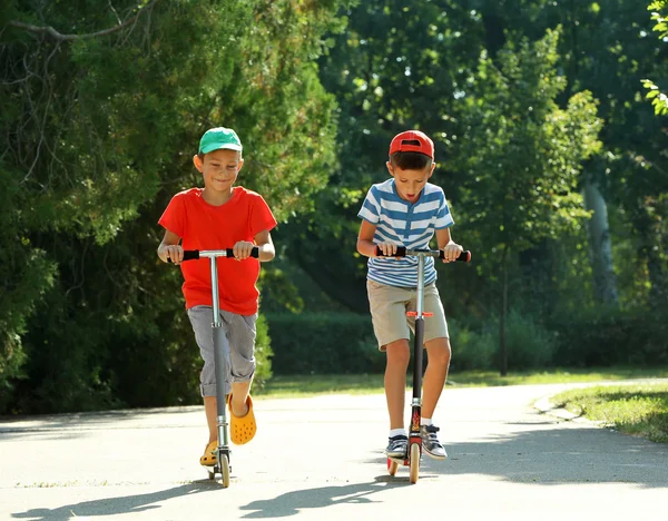 Meninos pequenos montando em scooters no parque — Fotografia de Stock