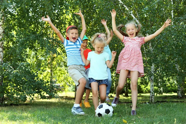 Feliz niños activos jugando con el fútbol en el parque — Foto de Stock