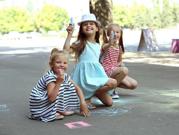 Щасливі активні діти малюють крейдою на асфальті — стокове фото