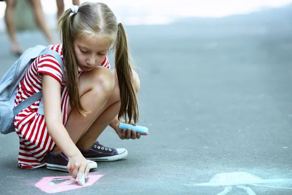 Милая маленькая девочка рисует мелом на асфальте — стоковое фото
