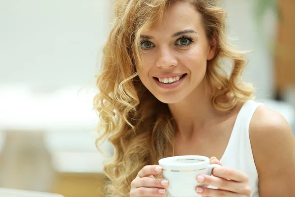 Mooie jonge vrouw drinken koffie in café — Stockfoto