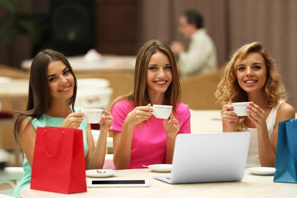 Hermosas mujeres jóvenes con ordenador portátil en la cafetería —  Fotos de Stock