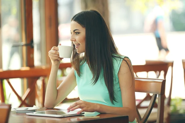 Bella giovane donna con tablet digitale in caffè — Foto Stock