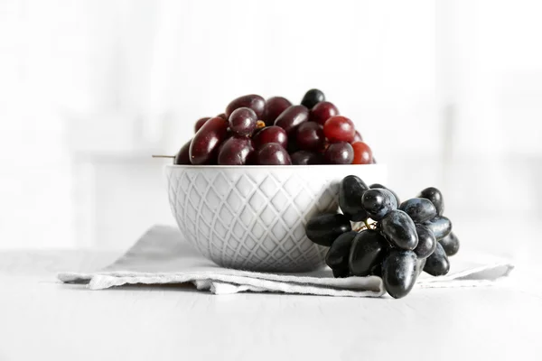 Verse rijpe druiven in kom op houten tafel — Stockfoto