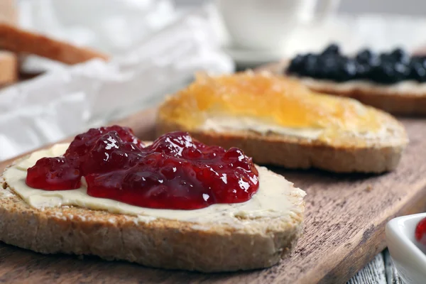 Färskt rostat bröd med smör och olika sylt på bordet på nära håll — Stockfoto