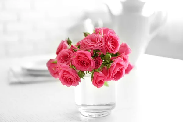 Hermosas flores en jarrón sobre la mesa, sobre fondo claro —  Fotos de Stock