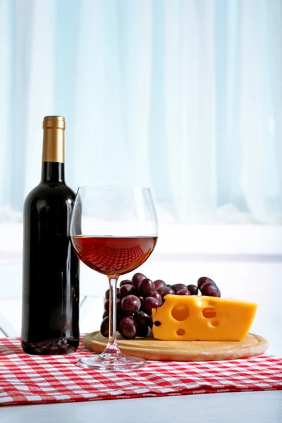 Kırmızı üzüm ve cam şişe şarapla hafif iç zemin üzerine peynir — Stok fotoğraf