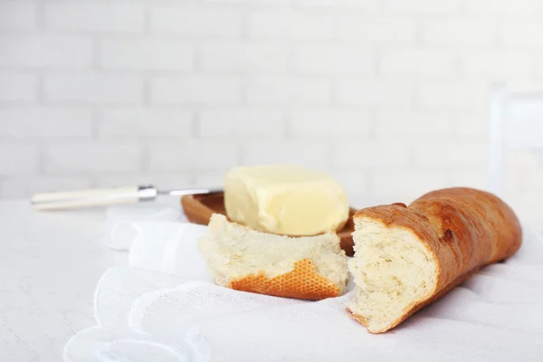 Broken baguette and butter on light background — Stock Photo, Image