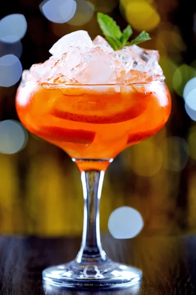 Glass of cocktail with ice on blurred lights background — Stock Photo, Image