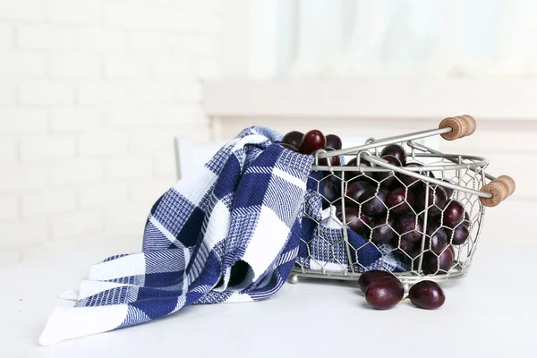 Ripe grapes in basket on table in kitchen — Stock Photo, Image