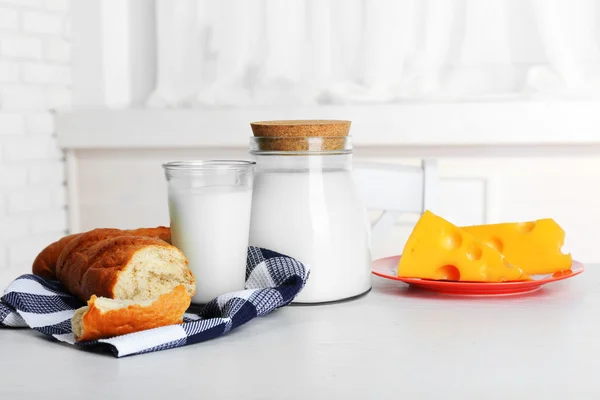 Milk with bread and cheese on table in kitchen — Stock Photo, Image