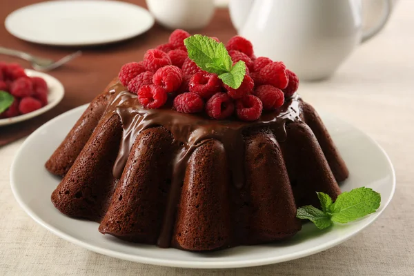 Tasty chocolate muffin with glaze and raspberries on table close up — Stock Photo, Image