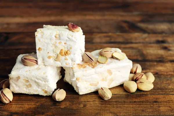 Sweet nougat with pistachios on wooden background