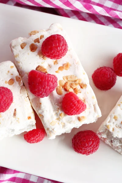 Turrón dulce con nueces y frambuesas en el plato de cerca —  Fotos de Stock