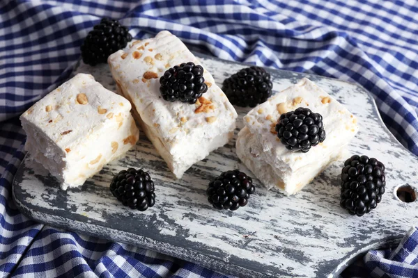 Sweet nougat with nuts and blackberries on cutting board close up — Stock Photo, Image