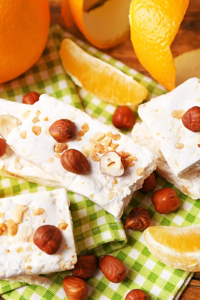 Sweet nougat with hazelnuts and oranges on table close up — Stock Photo, Image