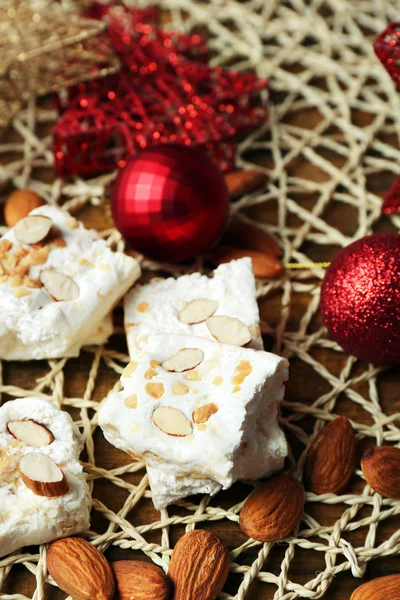 Torrone dolce con mandorle e tavola di addobbi natalizi da vicino — Foto Stock