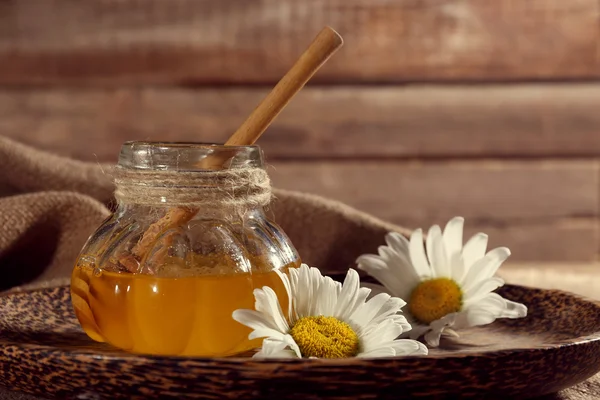 Pot of honey on tray with chamomile on wooden table — Stock Photo, Image