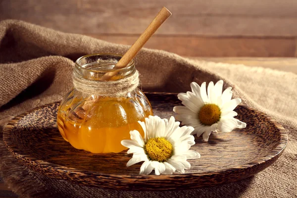 Pot of honey on tray with chamomile on wooden table — Stock Photo, Image