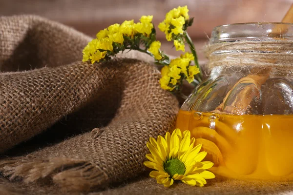 Jar of honey with flowers on sackcloth, close-up — Stock Photo, Image