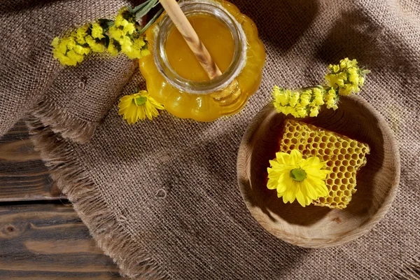 Банка мёда, соты и цветы на мешковине, вид сверху — стоковое фото