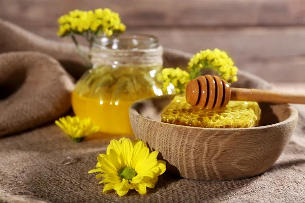 Maceta de miel, panal de abeja y cazo en tazón en saco sobre fondo de madera — Foto de Stock