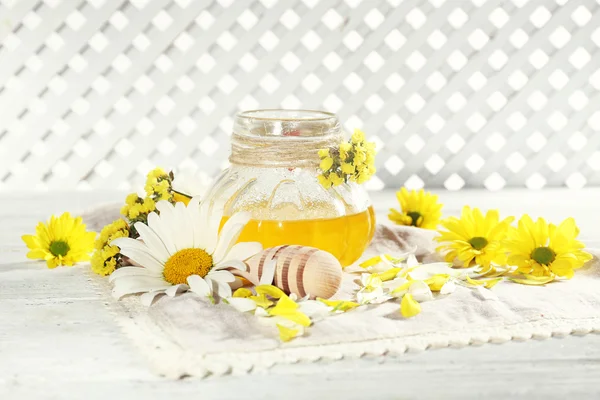 Honey and flowers on napkin on wooden table — Stock Photo, Image