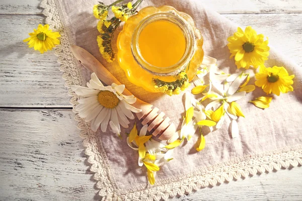 Honey and flowers on napkin on wooden background — Stock Photo, Image