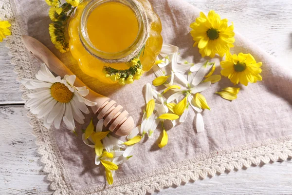 Honey and flowers on napkin on wooden background — Stock Photo, Image