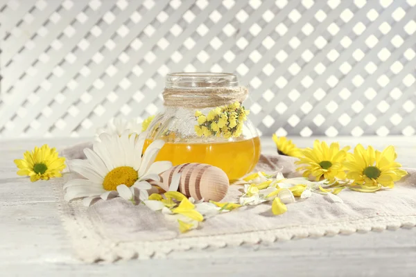 Honey and flowers on napkin on wooden table — Stock Photo, Image