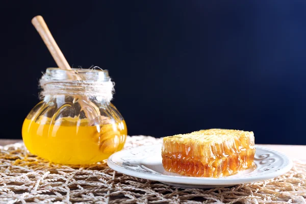 蜂蜜、木製ディッパー、暗い背景にハニカムの鍋 — ストック写真