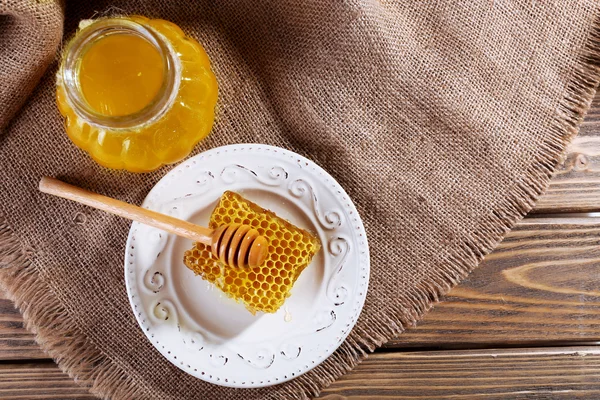 Topf mit Honig und Wabe mit Löffel auf Holzgrund — Stockfoto