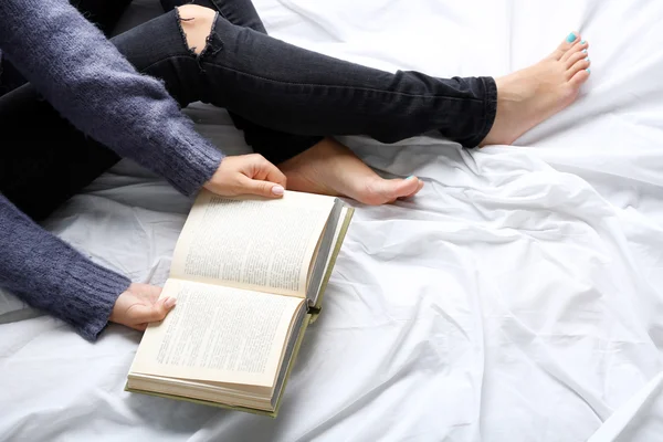 Mulher de jeans preto livro de leitura na cama ponto de vista superior — Fotografia de Stock