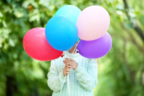 Menina segurando balões perto do rosto — Fotografia de Stock