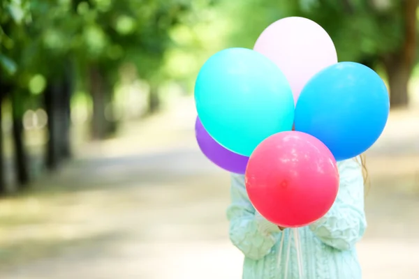 Flicka innehav ballonger nära ansikte — Stockfoto