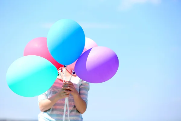 Flicka innehav ballonger nära ansikte — Stockfoto