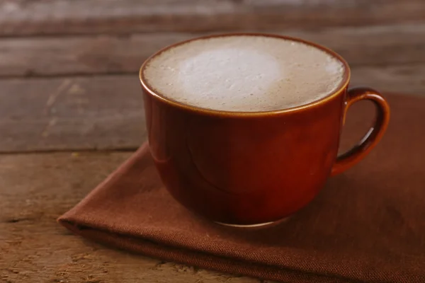 Cup of coffee on napkin on wooden background — Stock Photo, Image