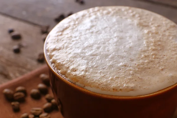 Tazza di caffè su tovagliolo e chicchi di caffè su sfondo di legno — Foto Stock