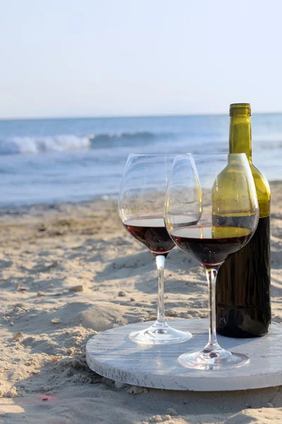 Botella de vino y copas en la orilla del mar — Foto de Stock