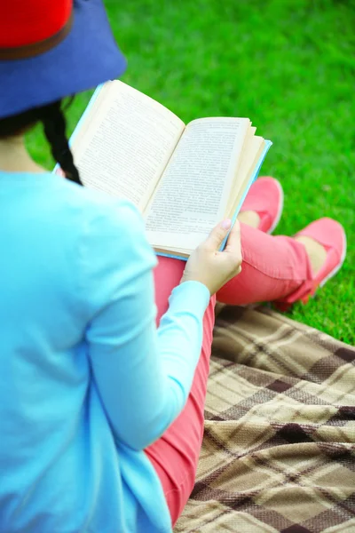 Mujer joven con libro sentado en la hierba verde al aire libre — Foto de Stock