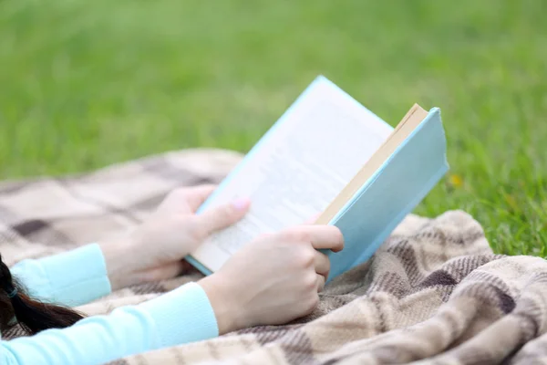 Młoda kobieta z książki leżące na zielonej trawie na zewnątrz — Zdjęcie stockowe