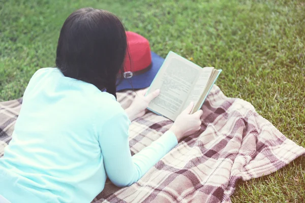 Young woman with book lying on green grass outdoors — Stock Photo, Image