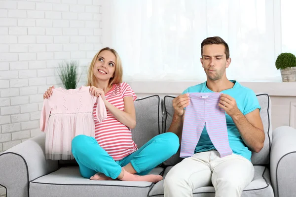 Young pregnant woman with husband on sofa in room Stock Photo