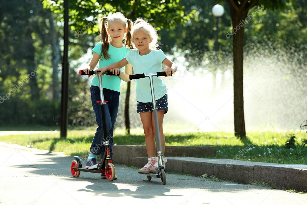 Small girls riding on scooters in park