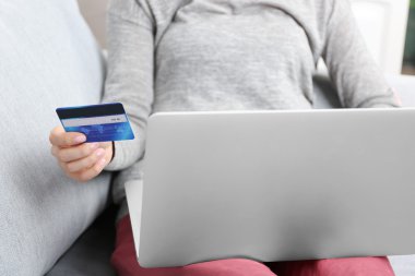 Internet alışveriş için kavram: dijital tablet ve kredi kartı kanepeye, evde oturan kadın ile