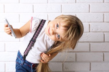 Güzel küçük kız ışık duvar arka plan üstünde hareket eden telefon ile