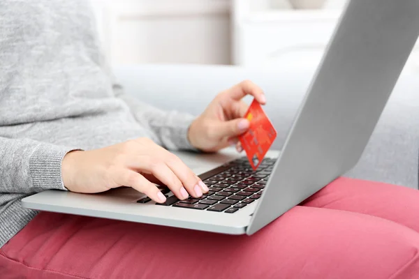 Concepto para compras por Internet: mujer con portátil y tarjeta de crédito sentada en el sofá, en casa —  Fotos de Stock