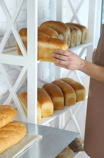 Panadero sosteniendo pan recién horneado en la cocina de la panadería — Foto de Stock